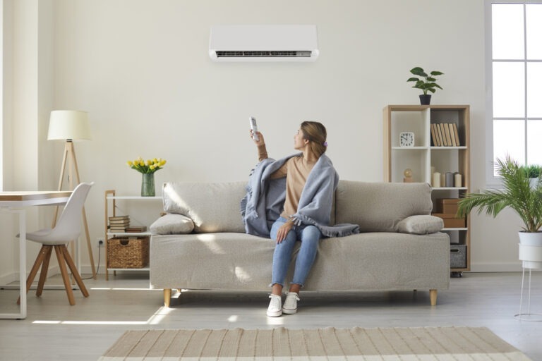 Mujer disfrutando del fresco de su aire acondicionado en el salón de su casa